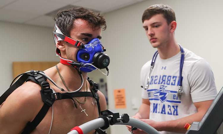 teacher and students affixing a breathing apparatus to an athlete